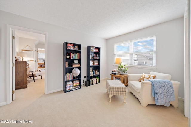 living area featuring light colored carpet, a textured ceiling, and baseboards