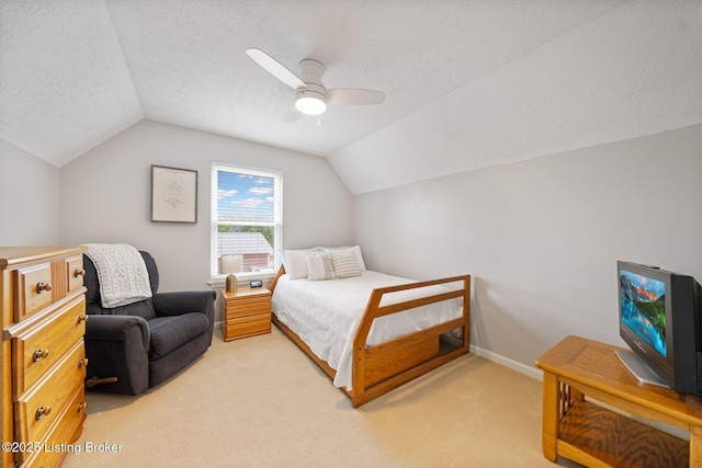 bedroom featuring vaulted ceiling, light colored carpet, a textured ceiling, a ceiling fan, and baseboards