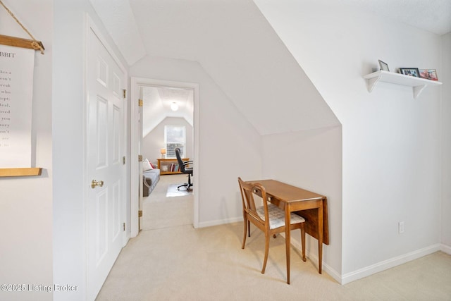 additional living space with vaulted ceiling, light colored carpet, baseboards, and an office area