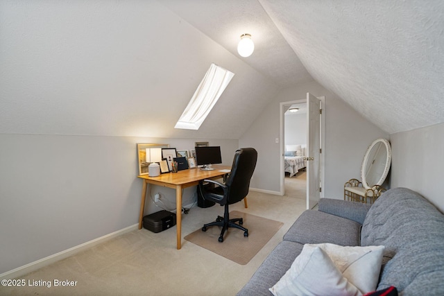 office area with a textured ceiling, vaulted ceiling, light carpet, baseboards, and a skylight