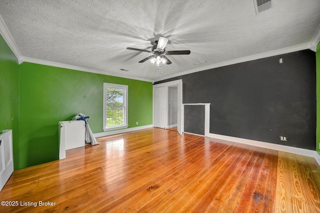 empty room with wood finished floors, ceiling fan, crown molding, baseboards, and a textured ceiling