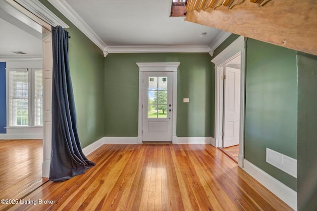 foyer with light wood finished floors, ornamental molding, and baseboards
