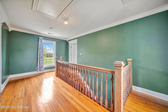 unfurnished room with attic access, baseboards, hardwood / wood-style floors, and ornamental molding