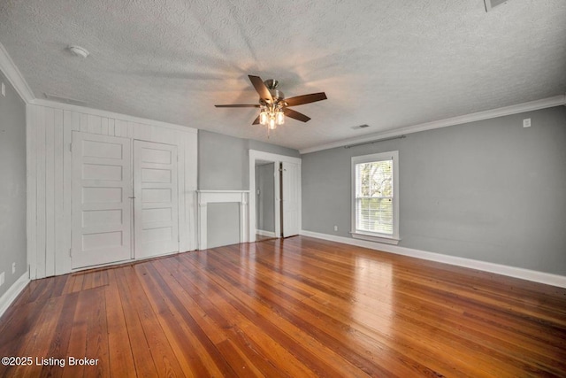 unfurnished bedroom with a textured ceiling, wood-type flooring, ornamental molding, baseboards, and a ceiling fan