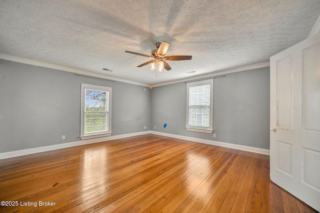 unfurnished room featuring wood-type flooring, a ceiling fan, a textured ceiling, baseboards, and crown molding