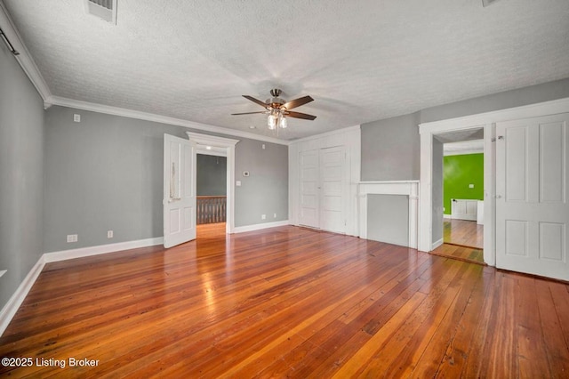 unfurnished living room featuring ceiling fan, wood-type flooring, a textured ceiling, baseboards, and crown molding
