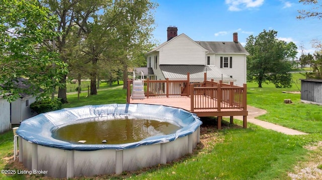 view of swimming pool featuring a deck, a yard, and a covered pool