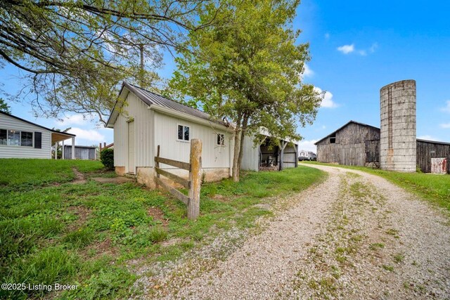 view of side of home featuring a barn, an outbuilding, board and batten siding, driveway, and metal roof