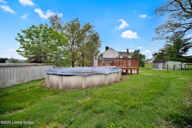 view of green lawn featuring a deck, an outdoor structure, and a storage unit