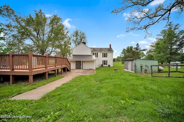 back of house featuring a deck, a chimney, an outbuilding, and a shed