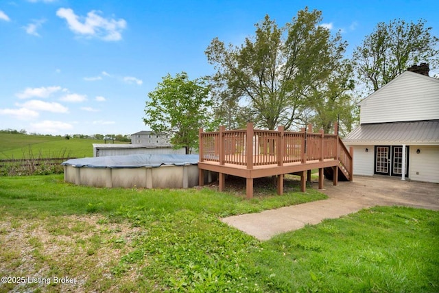 view of green lawn featuring a deck and a covered pool