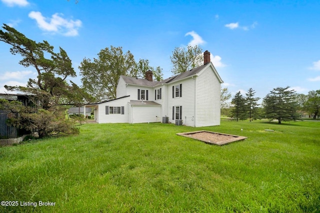 rear view of house featuring a chimney, a lawn, and central air condition unit