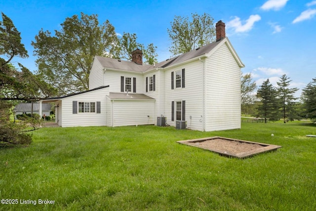 back of house featuring a chimney, cooling unit, and a yard