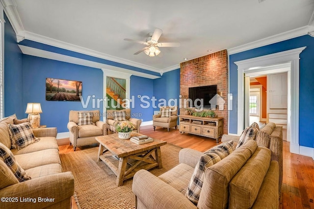 living area with light wood finished floors, a ceiling fan, crown molding, baseboards, and stairs