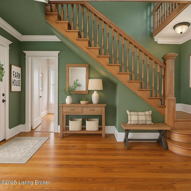 stairs with wood finished floors, baseboards, and ornamental molding