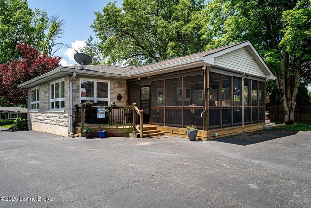 8703 Waltlee Rd, Louisville, KY 40291 - view of front of home featuring stone siding, a sunroom, and roof with shingles