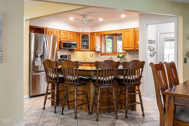 8703 Waltlee Rd, Louisville, KY 40291 - kitchen featuring stainless steel appliances, tasteful backsplash, a breakfast bar, light tile patterned floors, and ceiling fan