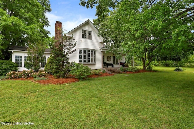 back of property featuring a chimney and a yard