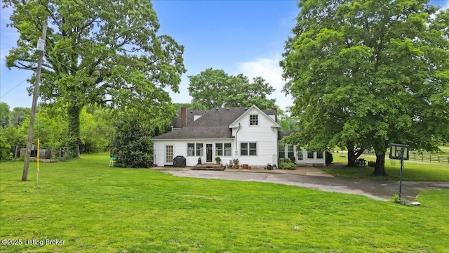 rear view of house featuring a chimney, a yard, and a patio