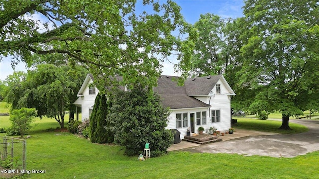 back of house featuring roof with shingles and a lawn