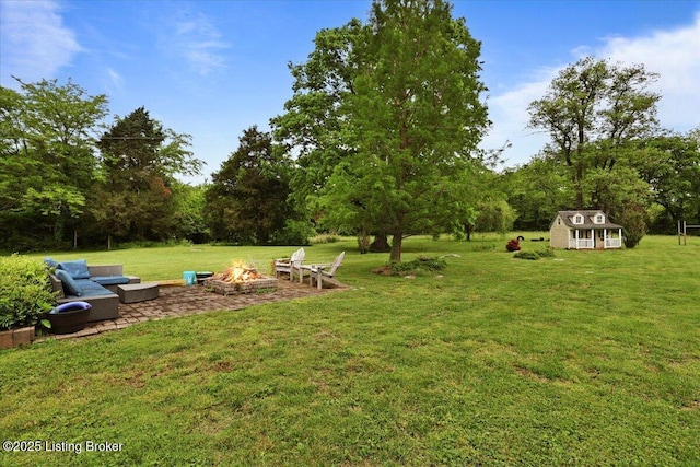 view of green lawn featuring an outdoor fire pit and an outbuilding