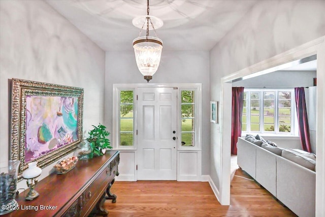 entryway with wood finished floors, a chandelier, and baseboards