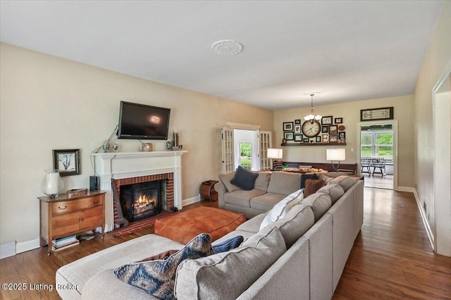 living area with wood finished floors, a brick fireplace, and baseboards