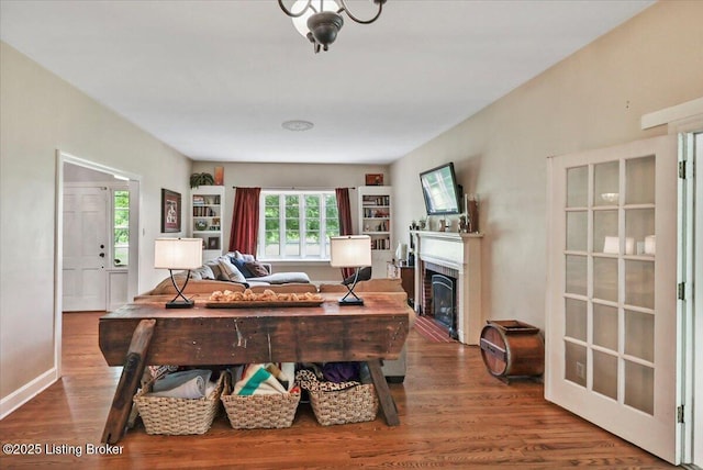 living area with wood finished floors, a glass covered fireplace, and baseboards