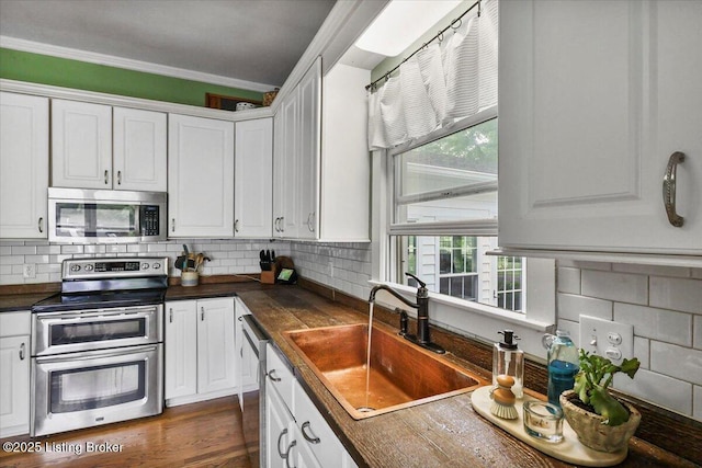 kitchen with stainless steel appliances, a sink, white cabinets, and ornamental molding