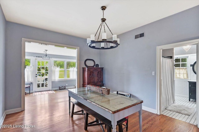 dining space featuring a chandelier, baseboards, and wood finished floors