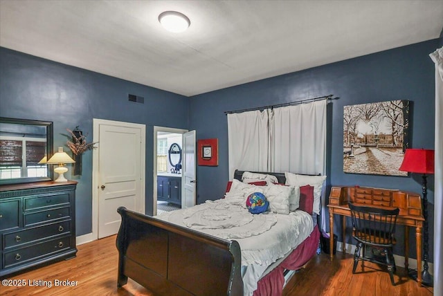 bedroom with wood finished floors and connected bathroom