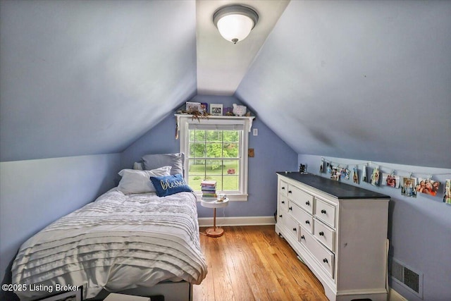 bedroom featuring light wood-style flooring, vaulted ceiling, and baseboards