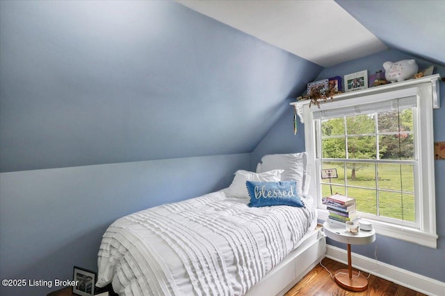 bedroom featuring lofted ceiling, baseboards, and wood finished floors