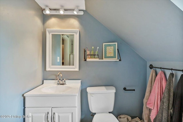 bathroom with lofted ceiling, vanity, and toilet