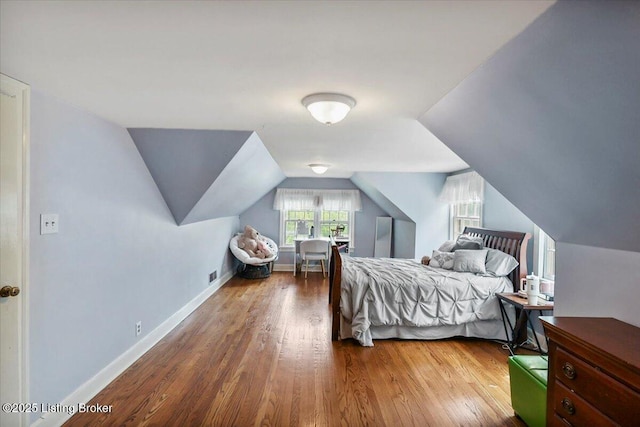 bedroom with wood finished floors, vaulted ceiling, and baseboards