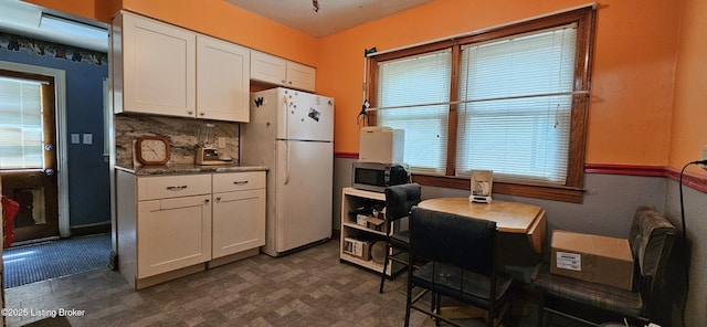 1766 Wilart Dr, Louisville, KY 40210 - kitchen featuring freestanding refrigerator, stainless steel microwave, white cabinets, decorative backsplash, and a desk