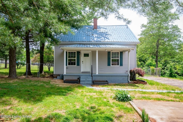 view of front of property featuring covered porch, a chimney, metal roof, and driveway
