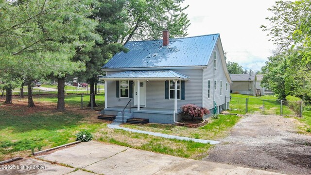 view of front of home with a porch, a chimney, metal roof, and a gate