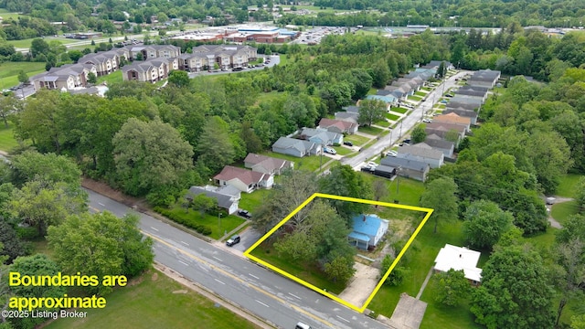 aerial view of residential area with property parcel outlined and a tree filled landscape
