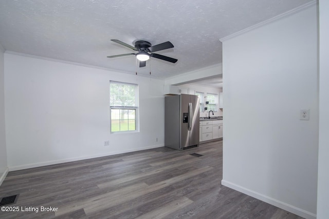 unfurnished living room with a ceiling fan, a sink, dark wood-type flooring, crown molding, and baseboards