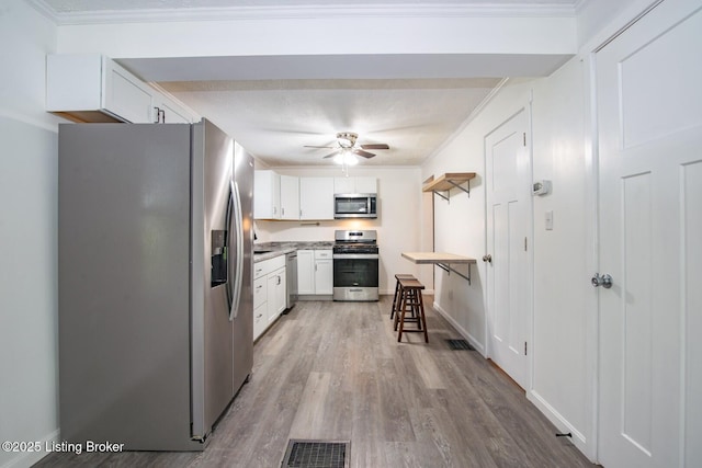 kitchen featuring stainless steel appliances, a ceiling fan, white cabinets, light wood-style flooring, and light countertops