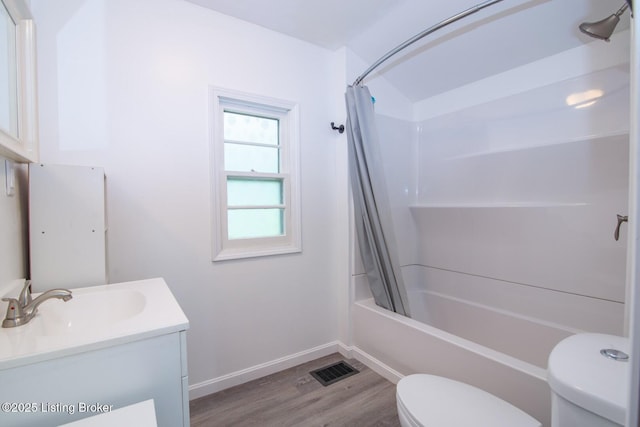 bathroom featuring toilet, wood finished floors, vanity, baseboards, and shower / tub combo