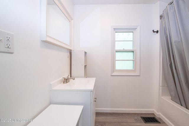 bathroom with vanity, wood finished floors, baseboards, and shower / tub combo