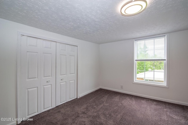 unfurnished bedroom with carpet flooring, a textured ceiling, baseboards, and a closet