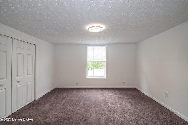 unfurnished bedroom featuring carpet floors, a textured ceiling, baseboards, and a closet