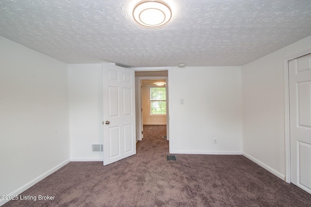empty room featuring carpet floors, a textured ceiling, and baseboards