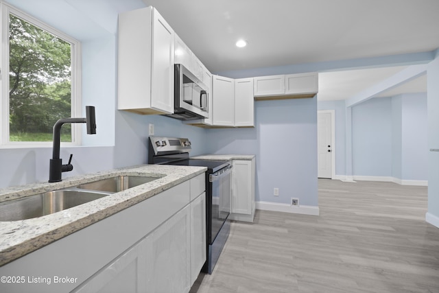 5319 New Cut Rd, Louisville, KY 40214 - kitchen featuring appliances with stainless steel finishes, a sink, light stone counters, white cabinetry, and light wood-style floors