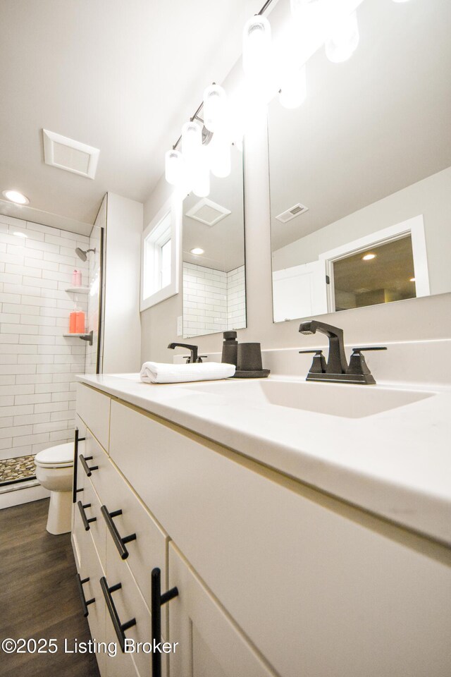 9206 Fox Chase Rd, Louisville, KY 40228 - bathroom featuring double vanity, toilet, tiled shower, wood finished floors, and recessed lighting