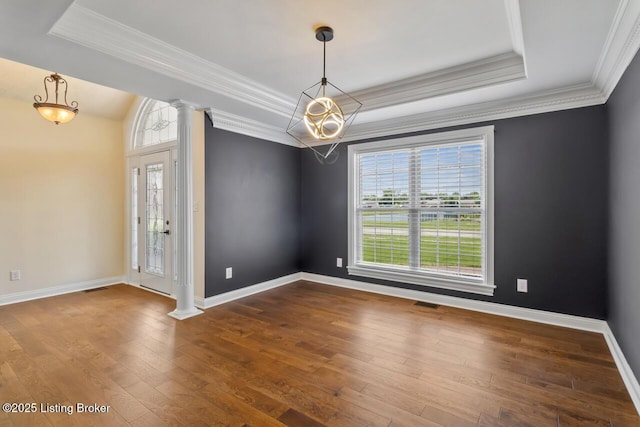 unfurnished room featuring decorative columns, a tray ceiling, a chandelier, dark wood-style floors, and crown molding