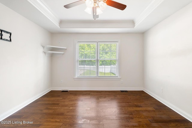 empty room featuring crown molding, a raised ceiling, dark wood-style floors, ceiling fan, and baseboards